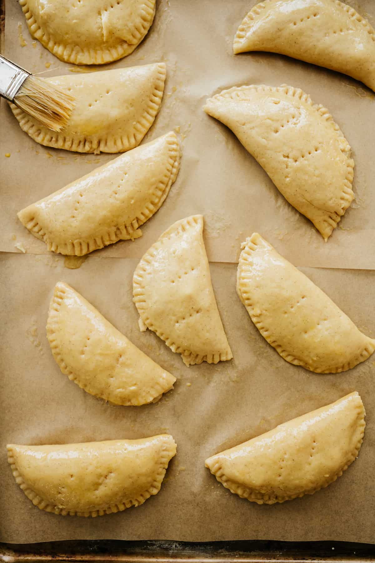 brushing crimped and fork-poked assembled empanadas with an egg wash before baking.