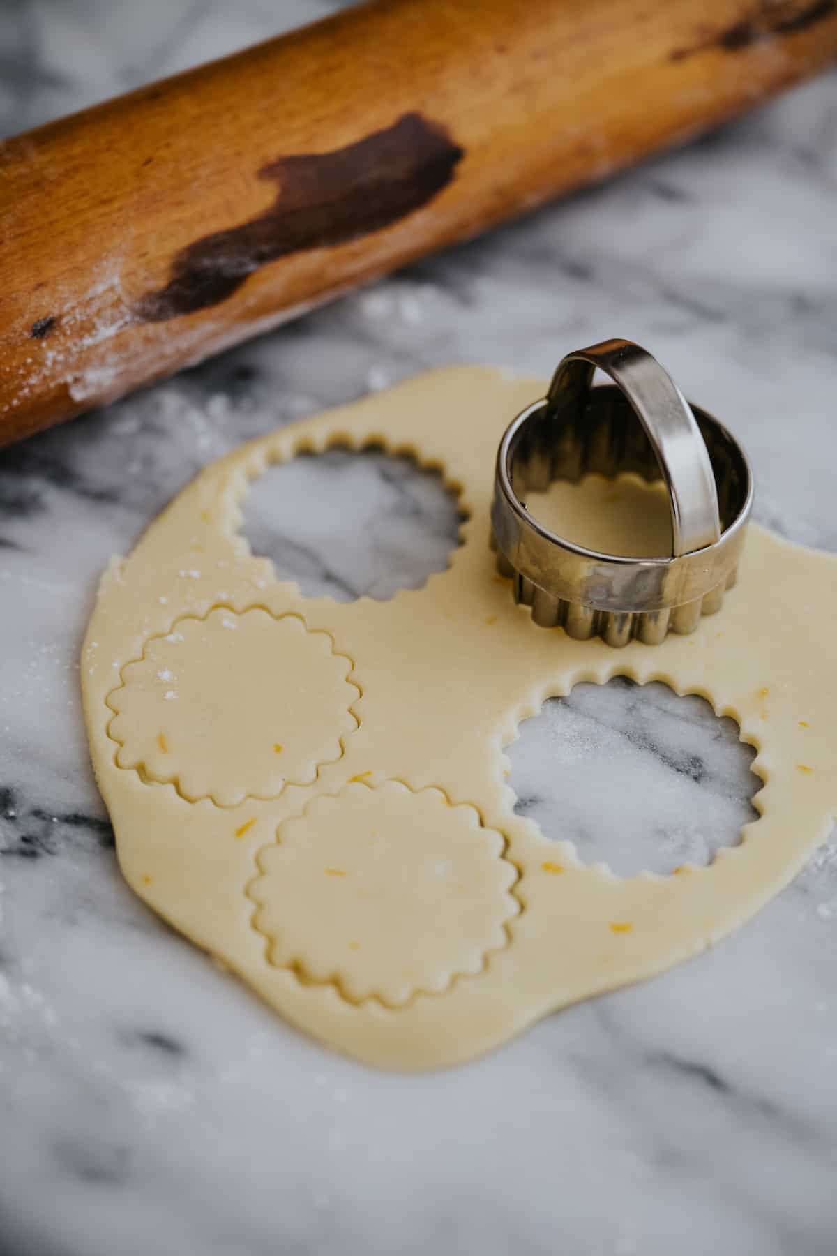stamping out scalloped-edged cookies from the rolled out dough for making alfajores.