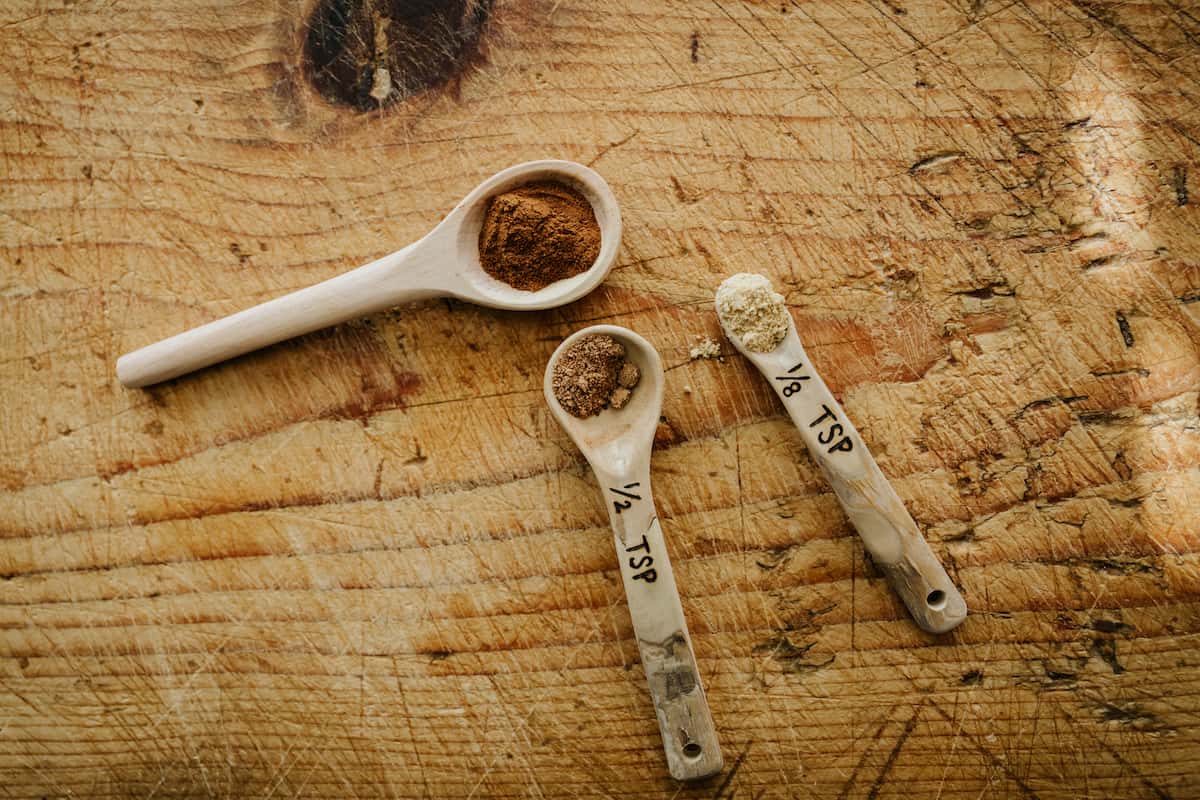 rustic wooden teaspoon measures filled with the spices used in the empanadas de piña pineapple filling.