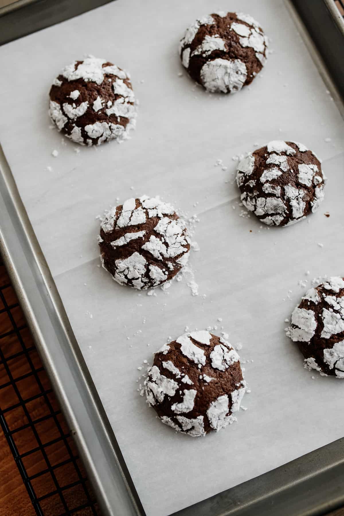 mexican chocolate crinkle cookies after baking on a parchment-lined baking sheet.