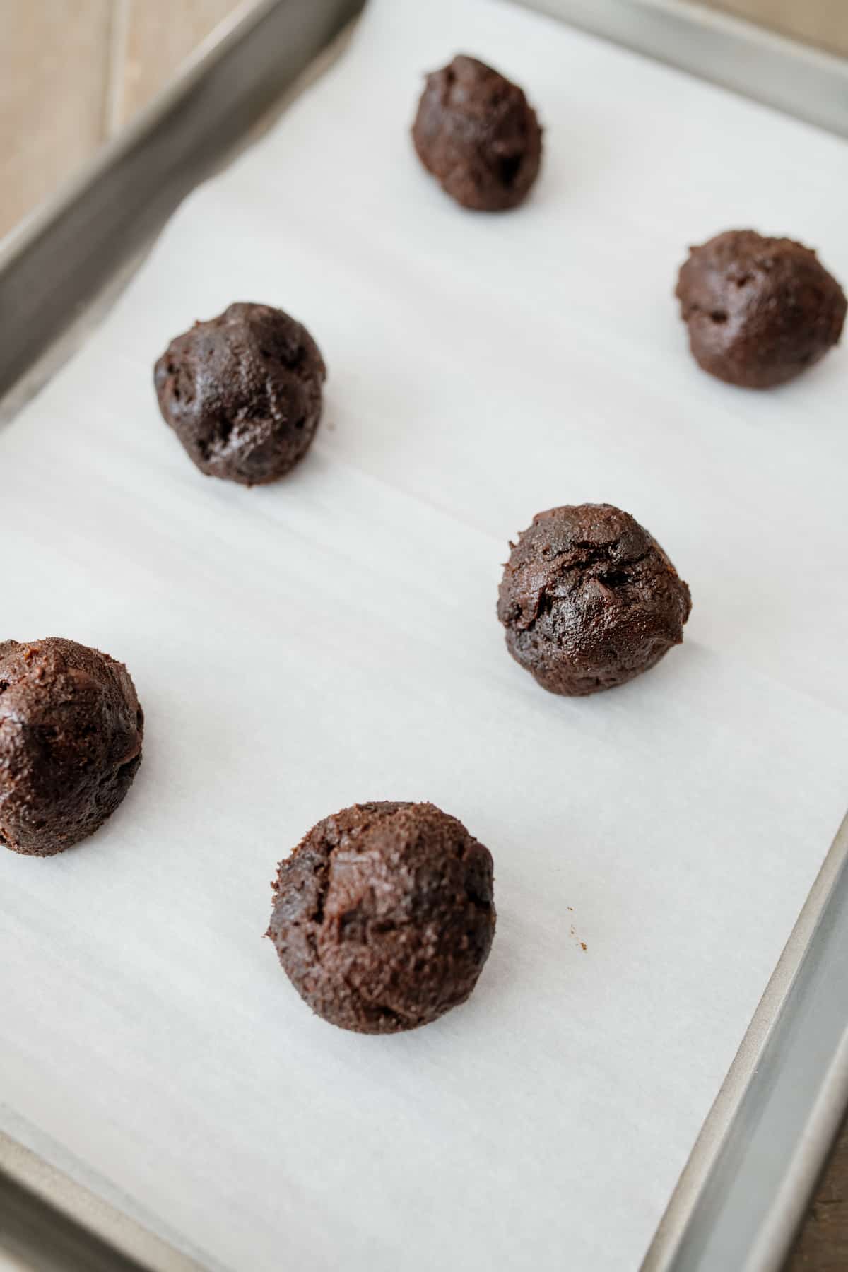 balls of mexican hot chocolate cookie dough on a parchment-lined sheet tray.