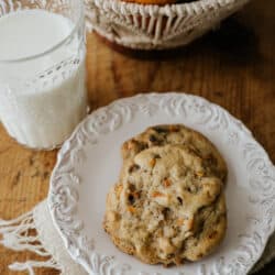 Fotografía cenital de 2 galletas de caqui en un plato blanco junto a un vaso de leche.