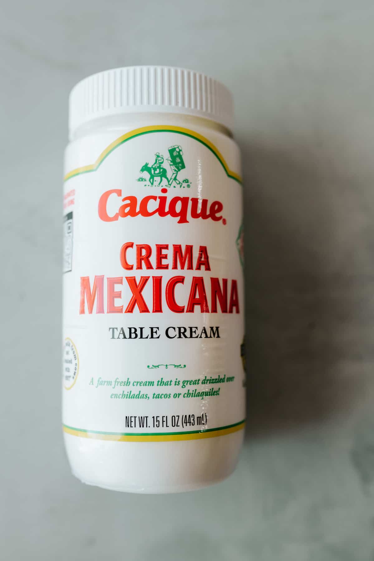 bottle of cacique brand crema mexicana on a grey table.
