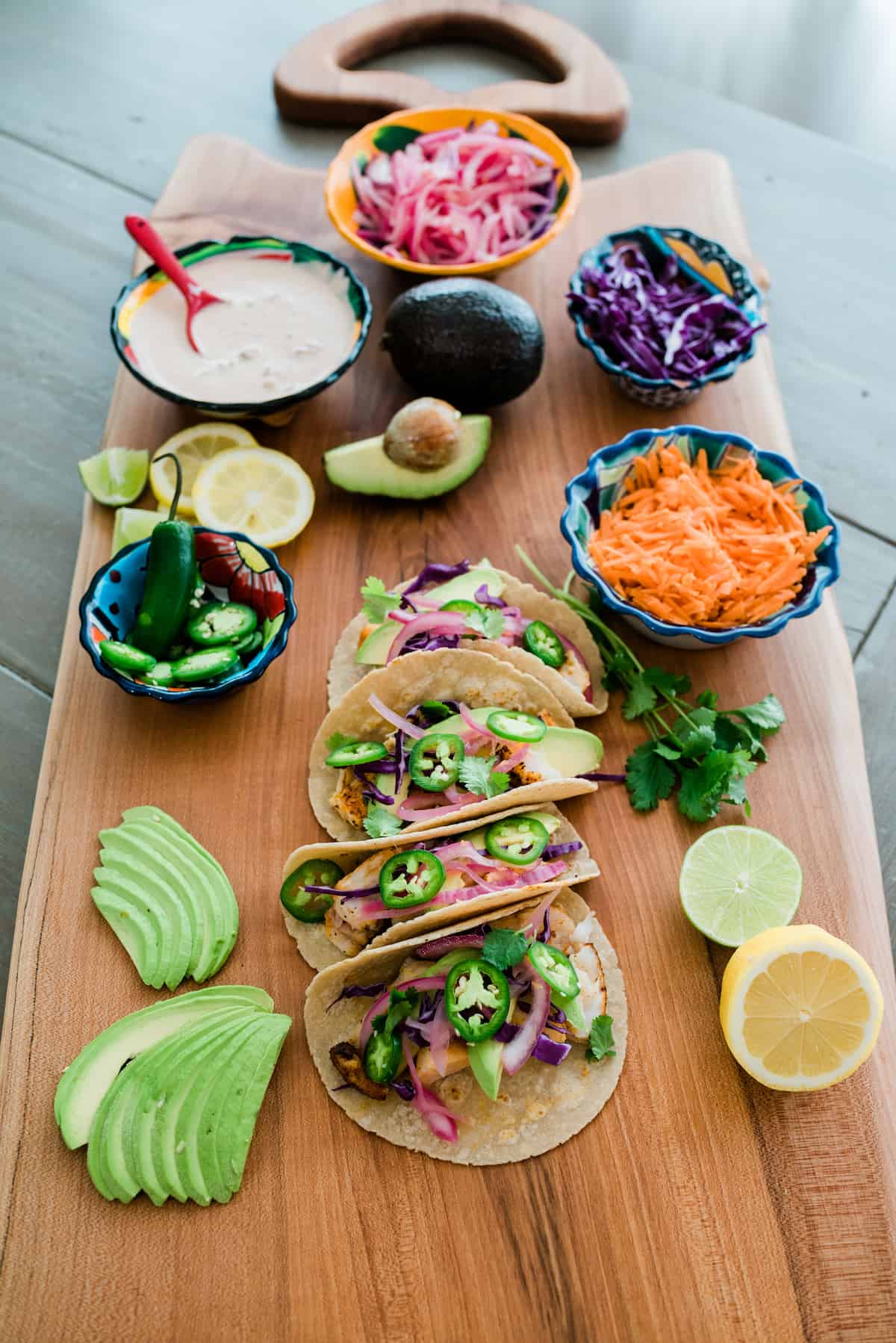 Taco party board with 4 assembled tilapia fish tacos and plenty of delicious sides and toppings to choose from.