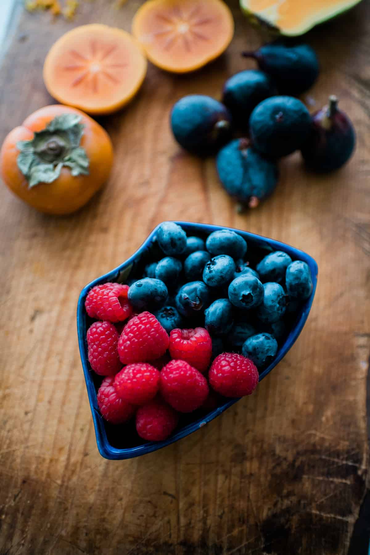 raspberries and blueberries in one sectioned bowl of a serving platter for making a yogurt parfait bowl.