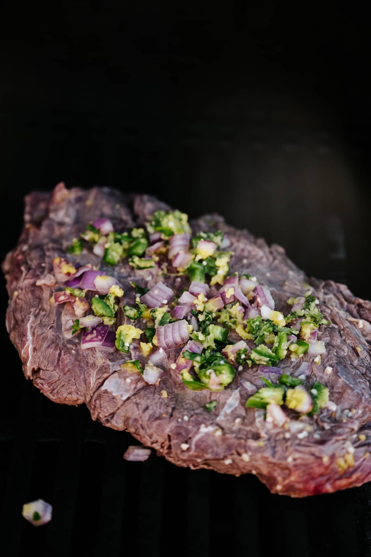carne asada marinated and grilled flank steak on a black surface.