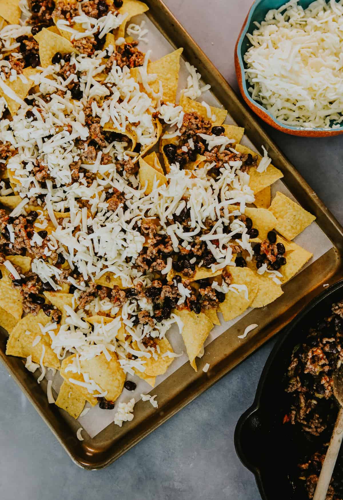 first layer of nacho tortilla chips on a parchment lined sheet pan topped with the black bean and beef mixture and sprinkled with shredded cheese before baking. 
